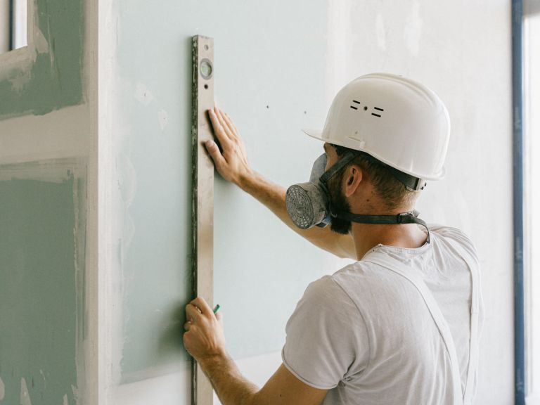 Handwerker richtet eine Platte mit der Wasserwaage an einer Wand aus